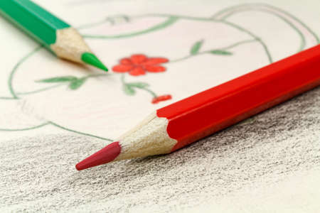 Red and green pencils on the background of a children's drawingの写真素材