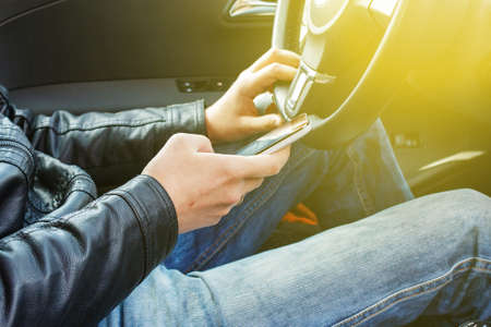 Driver behind the wheel of a car looking at the screen of the smartphone