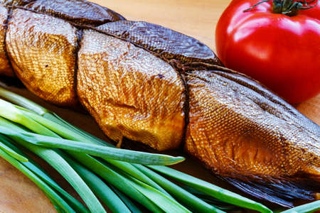 Smoked fish on cutting board with tomato and green onion closeupの写真素材