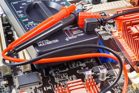 Digital multimeter with red and black probes on the computer motherboard closeupの写真素材