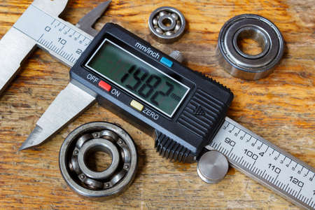 Electronic caliper with ball bearings on a wooden table in the workshopの写真素材