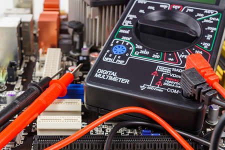 Digital multimeter with probes on the motherboard surface closeupの写真素材