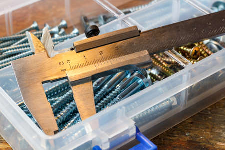 Slide calipers and self-tapping screws in a storage box on a workbenchの写真素材