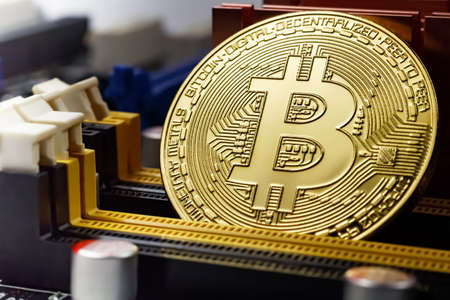 Golden bitcoin on the computer motherboard background closeup. Cryptocurrency virtual money