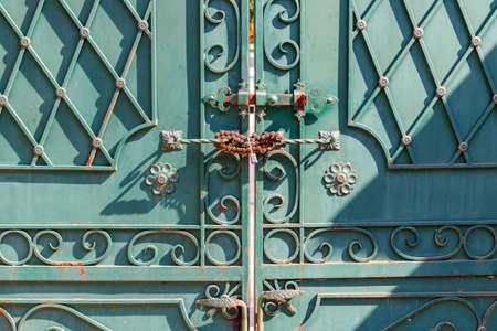 Fragment forged iron gate closed with a padlock closeup
