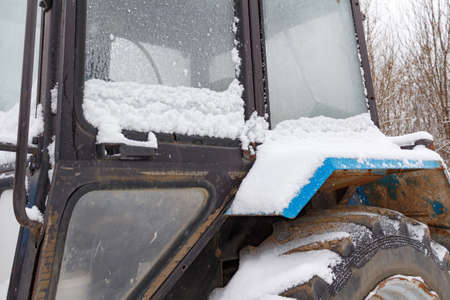Fragment of the old tractor cab covered with snow closeupの写真素材