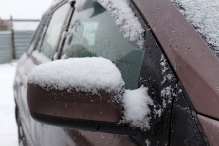 Dirty and snow covered SUV side mirror. Front view