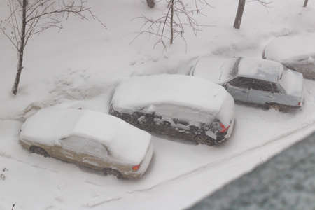 Snow-covered cars in the parking lot in a snowstormの写真素材