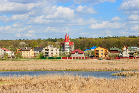 Village houses on the edge of a forest on the background of a lake overgrown with reedsの写真素材