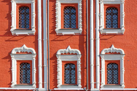 Windows with decorative metal grilles on the facade of red brick of ancient house closeupの写真素材