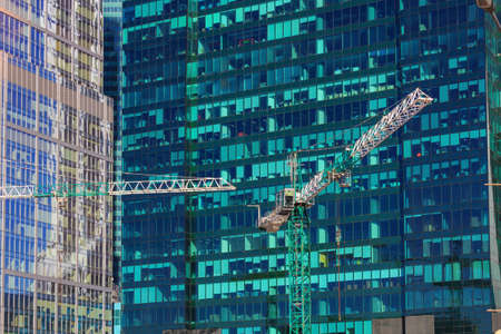 Moscow, Russia - April 14, 2018: Construction cranes on the background of glass facades of international business center Moscow city in sunny dayのeditorial素材