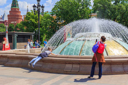 Moscow, Russia - June 03, 2018: Young woman with little girl takes a photo on a background of fountain on Manezhnaya Square in sunny summer morningのeditorial素材