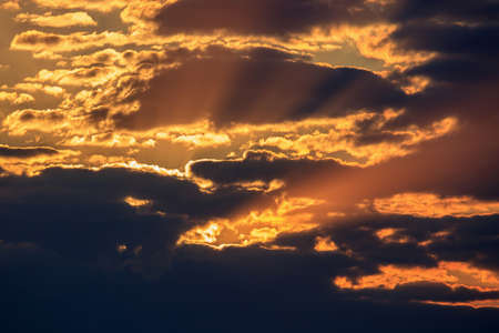 Dramatic sky with dark clouds and orange rays of the sun