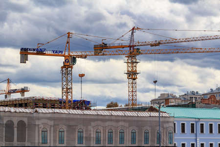 Moscow, Russia - September 30, 2018: Construction cranes in the center of Moscow on the background of reconstructed buildings against sky with grey dramatic cloudsのeditorial素材