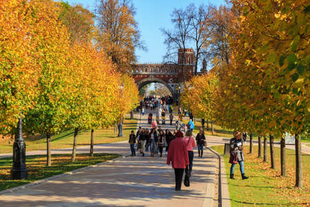 Moscow, Russia - October 17, 2018: Tourists walking on alley among trees with colored leaves in Tsaritsyno park in Moscow at sunny autumn dayのeditorial素材