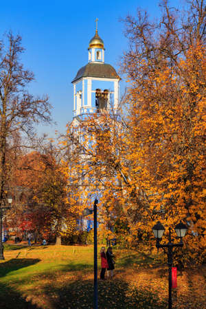 Moscow, Russia - October 17, 2018: People walking on lawn covered with colored leaves against Church of the icon of the mother of God in Tsaritsyno park in Moscow at sunny autumn dayのeditorial素材
