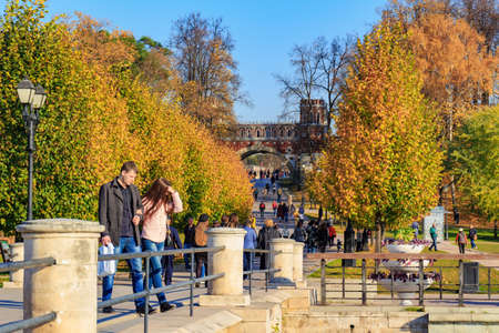 Moscow, Russia - October 17, 2018: Tourists walking on alley among trees with golden leaves at sunny...