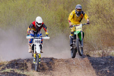Moscow, Russia - April 13, 2019: Two racers on a cross-country motorcycles jumps on a dirt track....