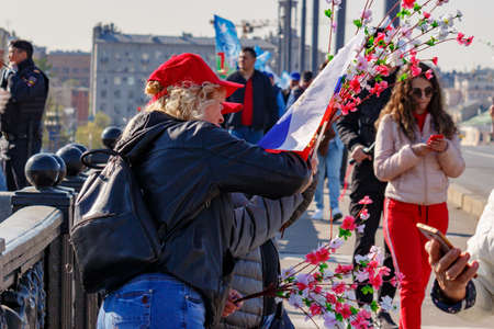 Moscow, Russia - May 01, 2019: Womans with flag and flowers go to the May Day demonstration on Red Square. May Day celebration in Moscowのeditorial素材