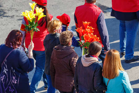 Moscow, Russia - May 01, 2019: Peoples with flowers go to the May Day demonstration on Red Square....