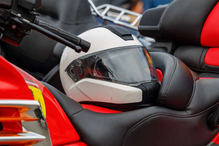 Moscow, Russia - May 04, 2019: White motorcycle helmet with closed visor lies on a leather seat of motorcycle closeup. Moto festival MosMotoFest 2019のeditorial素材