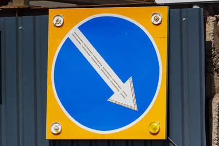 Temporary road sign with arrow indicating the direction of detour closeup