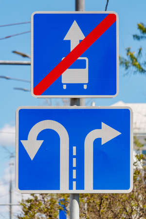Road signs Direction of motion traffic on the lanes closeup against green trees and blue sky in...