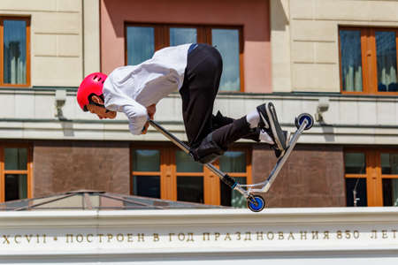 Moscow, Russia - June 02, 2019: Young flatland riders on sports scooters performs tricks at ramp on Manezhnaya Square in Moscow at sunny summer day. Festival Fish week in Moscow 2019のeditorial素材