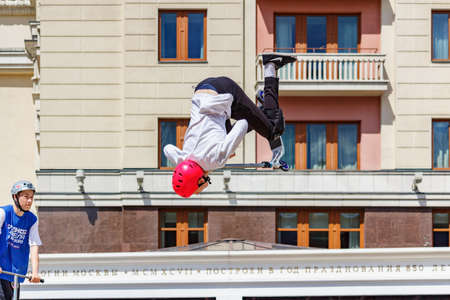 Moscow, Russia - June 02, 2019: Young flatland riders on sports scooters performs tricks at ramp on...
