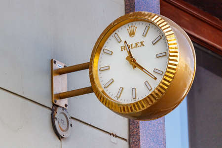 Moscow, Russia - June 02, 2019: Analogue street clock Rolex in golden case hanging on a wall above entrance to the showroom in the center of Moscowのeditorial素材