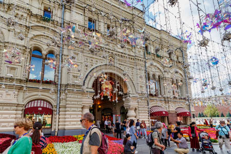 Moscow, Russia - July 28, 2019: Tourists are photographed on a flowerbeds background near GUM State Department Store in Moscow at sunny summer day. Traditional annual Flower Festival in GUMのeditorial素材