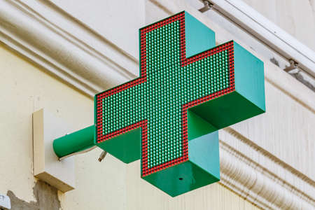 Moscow, Russia - September 13, 2019: LED green cross on the building wall close-up. Green cross is symbol of pharmacyのeditorial素材
