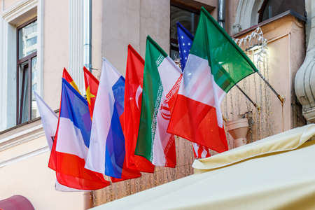 Waving flags of different countries in a row on the wall in sunlightの写真素材