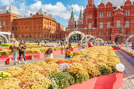 Moscow, Russia - October 08, 2019: Visitors of traditional festival Golden Autumn on Manezhnaya Square in Moscow takes a photo against colored flowers of decorative installations at sunny autumn dayのeditorial素材