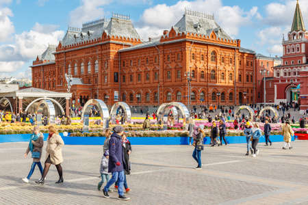 Moscow, Russia - October 08, 2019: People walking on Manezhnaya Square in Moscow at sunny autumn day during traditional festival Golden Autumn against decorative installationsのeditorial素材