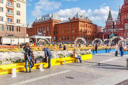 Moscow, Russia - October 08, 2019: People resting on the benches against decorative installations of traditional festival Golden Autumn in Moscow on Manezhnaya Squareのeditorial素材