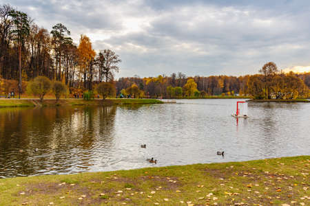Moscow, Russia - October 16, 2019: Tourists walking on Upper Pond embankment in Tsaritsyno Park at cloudy autumn day. Tsaritsyno Park is popular historical place in Moscowのeditorial素材