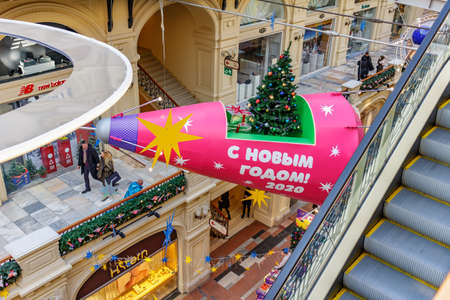 Moscow, Russia - November 21, 2019: Illuminated red spaceship with christmas tree and gifts on the board above alley of GUM State Department Store in Moscow. New Year interior of GUM on Red squareのeditorial素材
