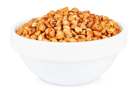 Dry buckwheat groats in a small white ceramic round bowl isolated on white backgroundの写真素材