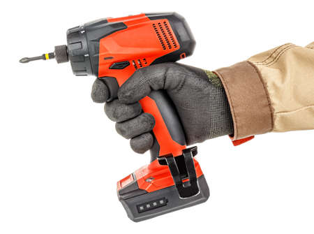 Modern red cordless screwdriver in worker hand in black protective glove and brown uniform isolated...