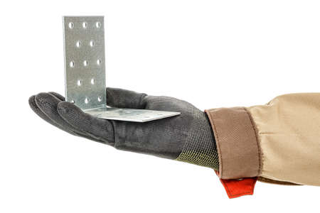 Galvanized metal mounting bracket with holes lies in palm of worker hand in black protective glove...