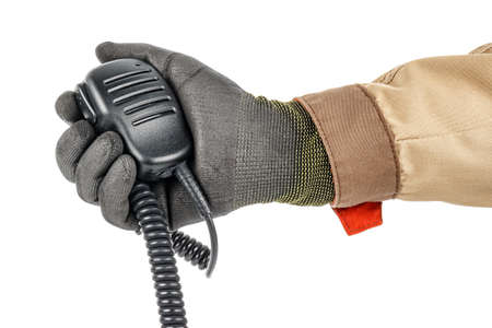 Walkie talkie handheld microphone with spiral connection cord in male hand in black protective glove and brown uniform isolated on white backgroundの写真素材