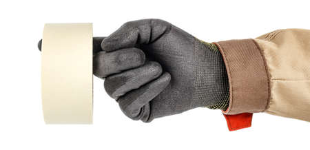Roll of paper masking tape hanging on finger of worker hand in black protective glove and brown...