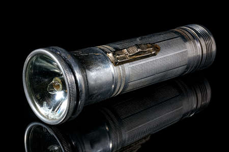 Vintage flashlight in aluminium case with a broken light bulb on black backgroundの写真素材