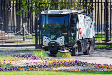 Moscow, Russia - May 01, 2019: Small sweepers truck clean paths of city park in sunny spring morning