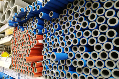 Moscow, Russia - August 17, 2019: Red and blue foam tubes for plumbing on the rack in a building...