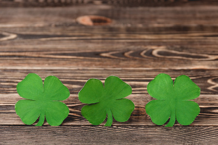 Four leaf clovers on brown wooden background