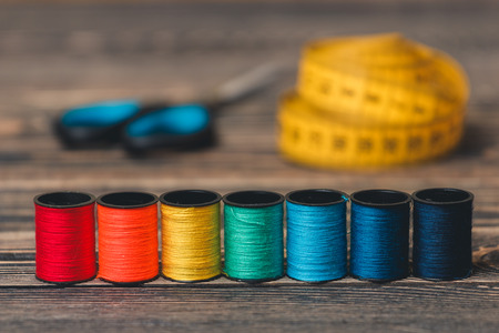 Sewing background with color threads, meter and scissors on brown wooden backgroundの写真素材