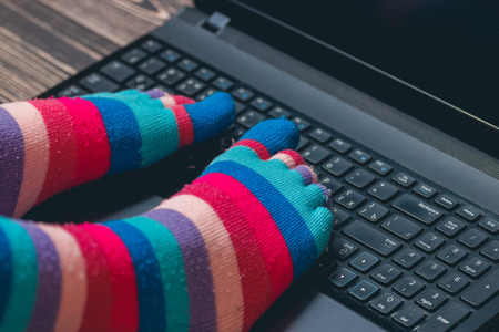 female legs in colorful striped socks on wooden backgroundの写真素材