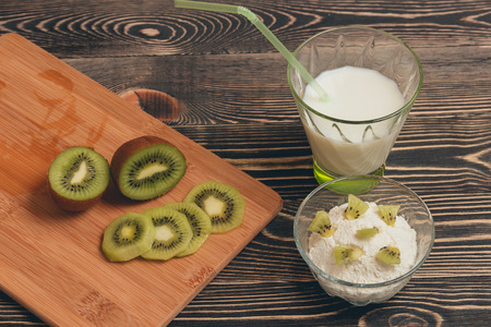 Glass of milk cocktail with kiwi fruits and mousse on wooden backgroundの写真素材